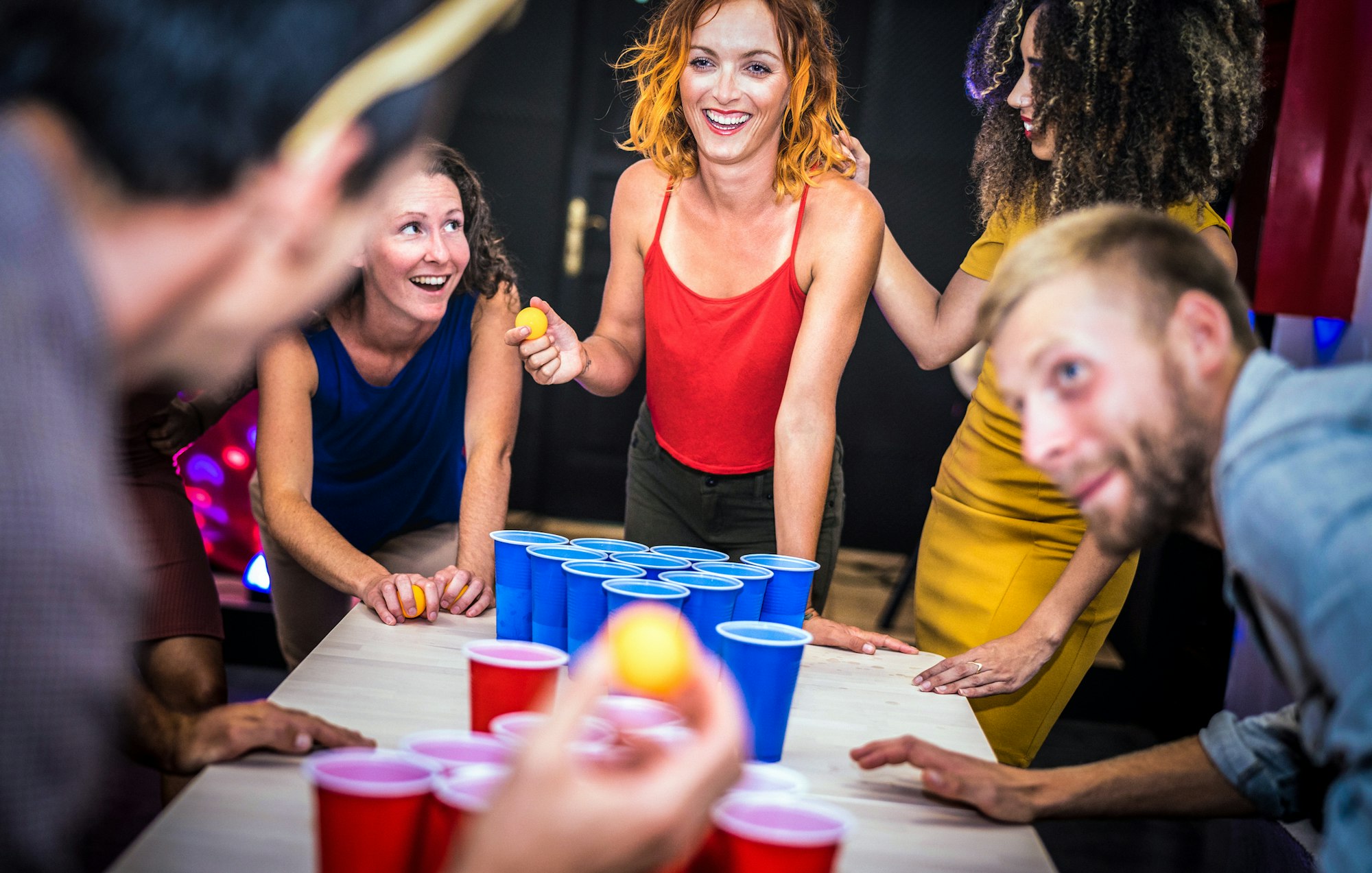 Young friends playing beer pong at youth hostel